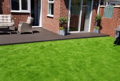 Photo of a grey composite deck with garden furniture and fake grass