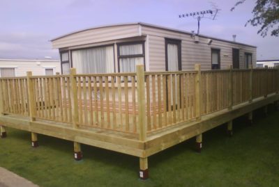 Photo of a raised decking installation with handrails going around a static caravan