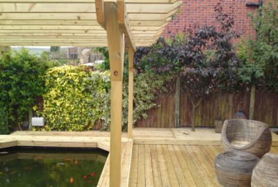 Photo of a decking and pergola installation over a pond, by Greenfield Leisure in Rotherham. With some rattan furniture