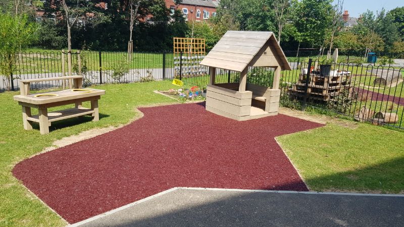 A photo of school playground safety surfacing. A red epoxy rubber bonded bark installation for a school in Sheffield.