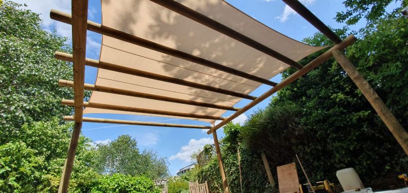 Closeup photo of a beige shade sail installed to a full log pergola