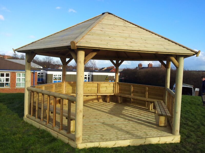 Outdoor timber gazebo with shiplap roof cladding and built-in seating, ideal as a school shelter.