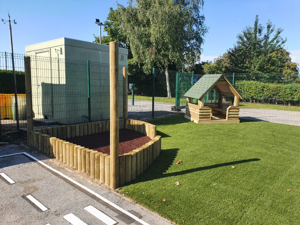 Children Aughton Log Cabin with artificial grass play area and sectioned-off space edged by upright log border